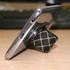 A phone stand in black with a geometric pattern, supporting a smartphone at an angle on a wooden surface.
