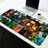A deluxe fabric gaming mat featuring various vibrant graphics in multiple colours, with a laptop and coffee cup on a table.