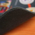 A textured black mouse mat with a fabric top, showcasing a slight curve at the edge.