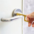 A gold No-Touch Door Opener is being used to pull a door handle, showcasing its sleek design.