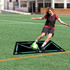 A football training mat in black with teal markings, set on a green field, with a player kicking a ball.