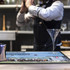A bar runner counter mat in black with a blue graphic, placed on a wooden bar top beside a martini glass.