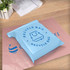 A light blue self-sealing plastic mailing bag on a pink background, featuring a logo.
