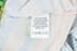 A care label on a 100% polyester micro mesh sports long sleeves shirt, featuring fabric care instructions.