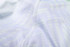 A close-up of a light-coloured, patterned fabric showcasing stitching details of a V-neck shirt.