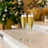 Two slanted champagne glasses filled with sparkling golden champagne, set against a festive holiday backdrop.