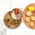 A round ceramic coaster featuring a colourful paisley design, with a drink and biscuits displayed alongside.