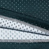 A close-up of a green and white fabric featuring a perforated texture, revealing layered materials with a stitching detail.