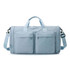 A foldable travel duffle bag in light blue with two front pockets and a detachable shoulder strap.