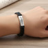A double-row braided leather bracelet in black, featuring a silver metal accent with a logo.