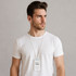 A man wearing a white T-shirt with a retractable ID card holder around his neck, featuring a silicone strap.