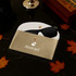 A gold PU leather glasses pouch with a white interior, holding a pair of black sunglasses. Features a logo.