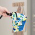 A lightweight mini auto umbrella in blue, white, and colourful patterns, held by a hand near a coat rack.
