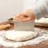 A beechwood handle flour cutter with a metal blade is shown cutting dough on a wooden surface, surrounded by flour.