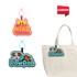 Custom felt hanging tags in pink and blue, featuring playful designs, attached to a beige tote bag.
