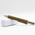 A cork pen with a silver clip, resting on a white block, featuring branding on the cork barrel.