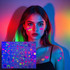 A model with colourful hair displays glow-in-the-dark temporary tattoos featuring various vibrant designs on her face and arms.