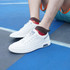 White sneakers worn with brown woven ankle socks, sitting on a blue court surface. The socks feature a custom pattern.