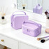 Two lavender portable mini suitcases are placed on a vanity, alongside makeup brushes and a decorative vase.