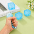 A blue squishy stress relief snowflake cube is being squeezed by a hand, with two more cubes in the background.