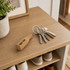 A drink bottle-shaped cork keyring in natural colour, attached to a set of keys, resting on a wooden table.