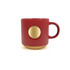 A red ceramic coffee mug featuring a bronze medal design and ribbed texture, with a curved handle.