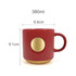 A ceramic coffee mug in red with a bronze medal detail, featuring a ribbed design and a handle.