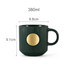 A green ceramic mug featuring a textured design and a bronze medal in the centre, with a capacity of 380ml.