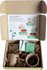 A growbox kit containing three peat pots, three peat pellets, plant labels, and seedsticks, inside a cardboard box.