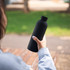 A drink bottle in matte black, featuring a double wall design, held in a person's hand against a blurred outdoor background.
