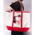 A large canvas tote bag in cream and red, featuring a logo and holding sunglasses and a drink bottle.