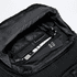 An open black backpack interior featuring a pen, a cardholder, and a small notebook.