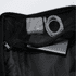 A black Eiger backpack interior featuring a metal device, tape, and a charging cable inside a mesh pocket.