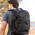 A black Fitzroy Backpack with multiple compartments and zippers, worn on the back of a person.