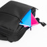 A black backpack partially unzipped, revealing a blue and a pink notebook inside. The backpack has a logo.