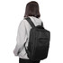 A black backpack is worn by a person in a grey hoodie, featuring staps and a top handle.
