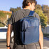 A navy Blackburn Backpack is carried on one shoulder by a person, featuring multiple compartments and a logo.