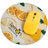 A round mouse pad in beige with lemon graphics and a yellow computer mouse on top. Features a logo.