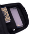 An open black backpack features a book and a phone inside a compartment, with a charging cable visible.