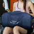 A navy canvas duffle bag with a logo, held by a person in sports attire, alongside a drink bottle.