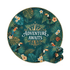 A round beach towel featuring a tropical design with green leaves, toucans, and flowers, folded beside it.