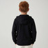 A zip-up hooded sweatshirt in black, displayed from the back on a child model. It features a hood.