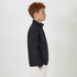 A youth jacket in black, featuring a collar and zip, displayed on a model from the side.