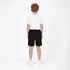 Youth Core Shorts in black showcased on a model wearing a white t-shirt, viewed from the back. Contains branding.