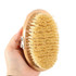 A sisal wooden brush held in a hand, featuring a light wooden base and natural bristles.
