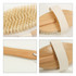 A detachable shower brush with a long wooden handle and a textured white strap, featuring soft bristles.