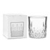 A crystal drink tumbler beside a white box with a simple geometric design. The tumbler is clear and features a faceted base.