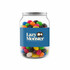 A clear jar filled with assorted jelly beans in various colours, featuring a label with a logo.