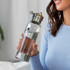 A drink bottle with a stainless steel lid, featuring clear glass and a green logo. The bottle is held by a woman in a blue top.