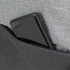 A smartphone in a grey fabric pocket of a black backpack with a zip.